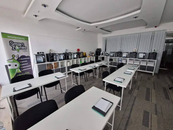 Berendezett bemutatóterem: Nyomtatók a polcokon, laptop és tablet minden asztalon